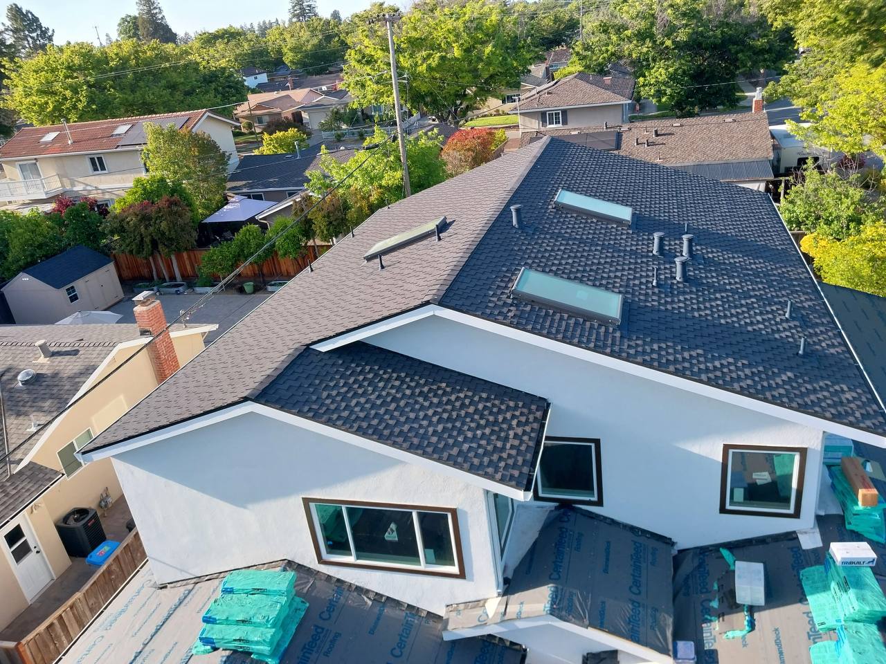 Wide aerial view of finished Charcoal Presidential TL Solaris roof over white stucco two-story home, San Jose